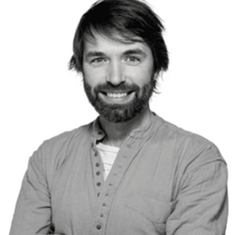 A black and white image of Jamie Fitzgerald, wearing a button-down shirt and smiling with his arms crossed.